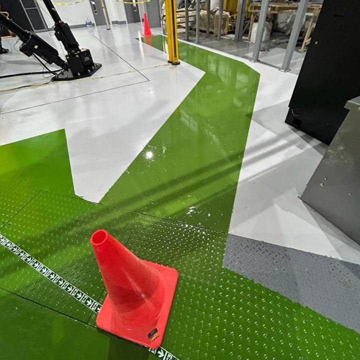 Green and white floor with a red traffic cone in an industrial setting