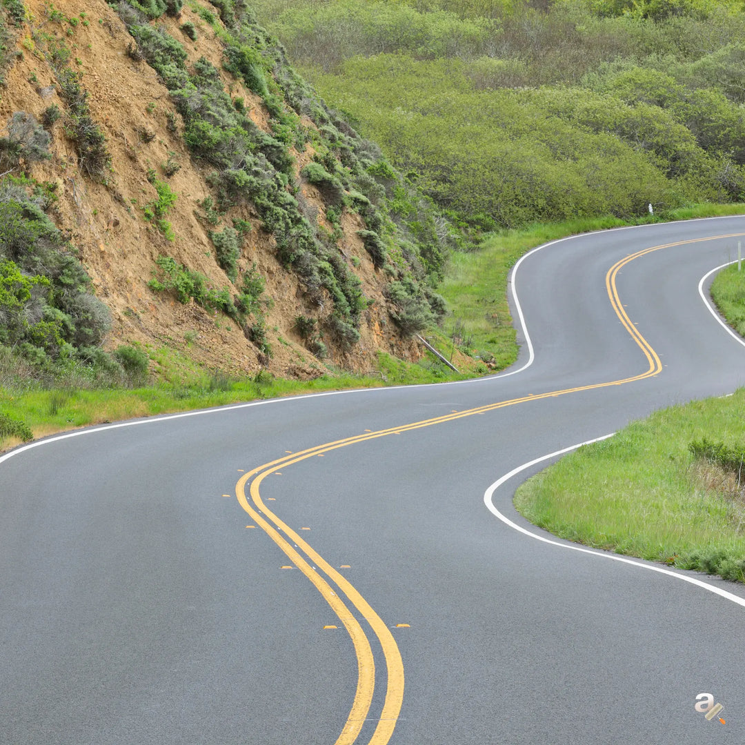 Winding road with double yellow lines on a green hillside