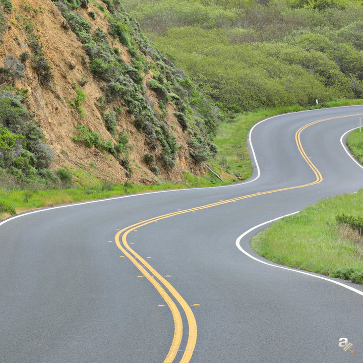 Winding road with double yellow lines on a green hillside