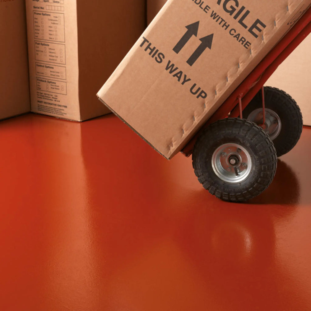 Cardboard box with 'This Way Up' and 'Glide With Care' labels on a red surface.