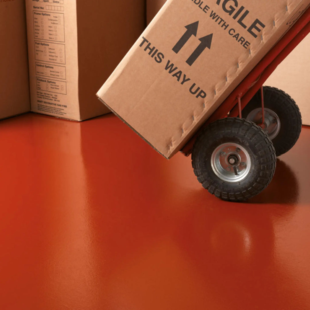 Cardboard box with 'This Way Up' and 'Glide With Care' labels on a red surface.