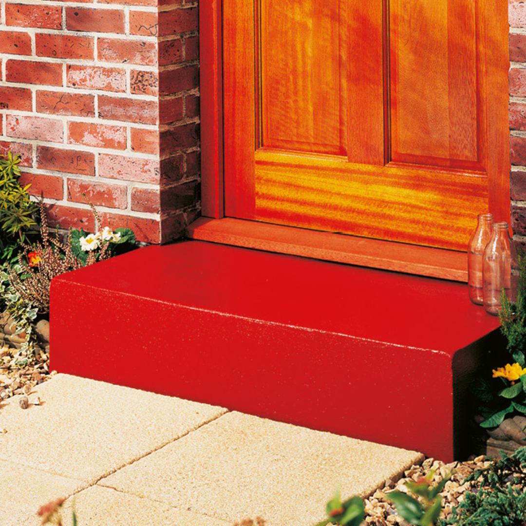 Red door threshold against a brick wall with a wooden door