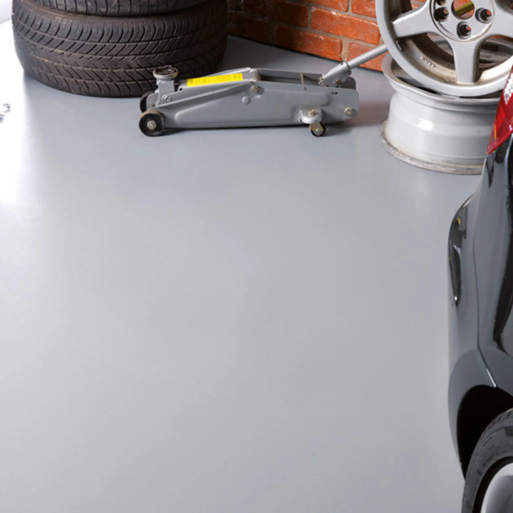 Car jack on a concrete floor with car parts in the background