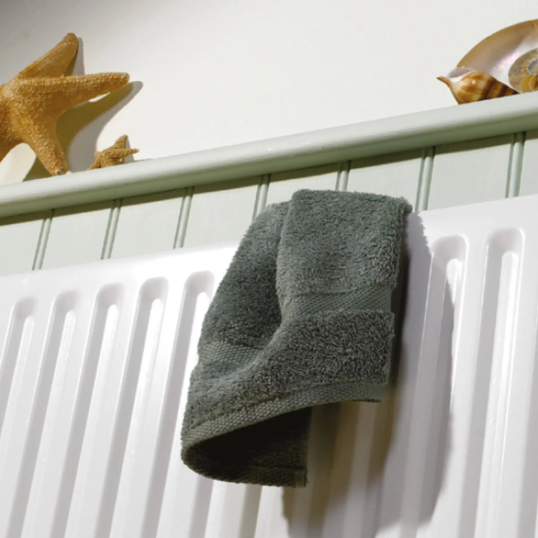 Gray towel hanging on a white radiator with decorative items above.