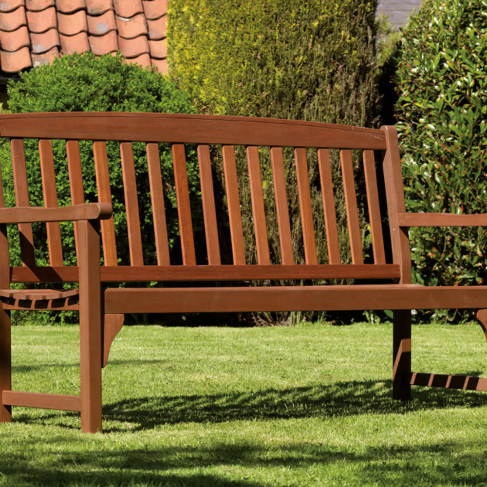 Wooden bench in a garden setting with green grass and trees.