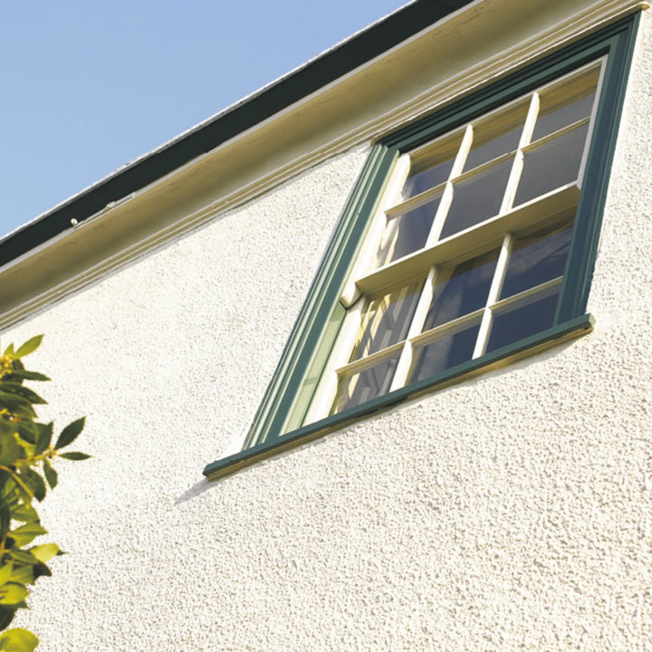 Window with green frame on a light-colored wall against a blue sky