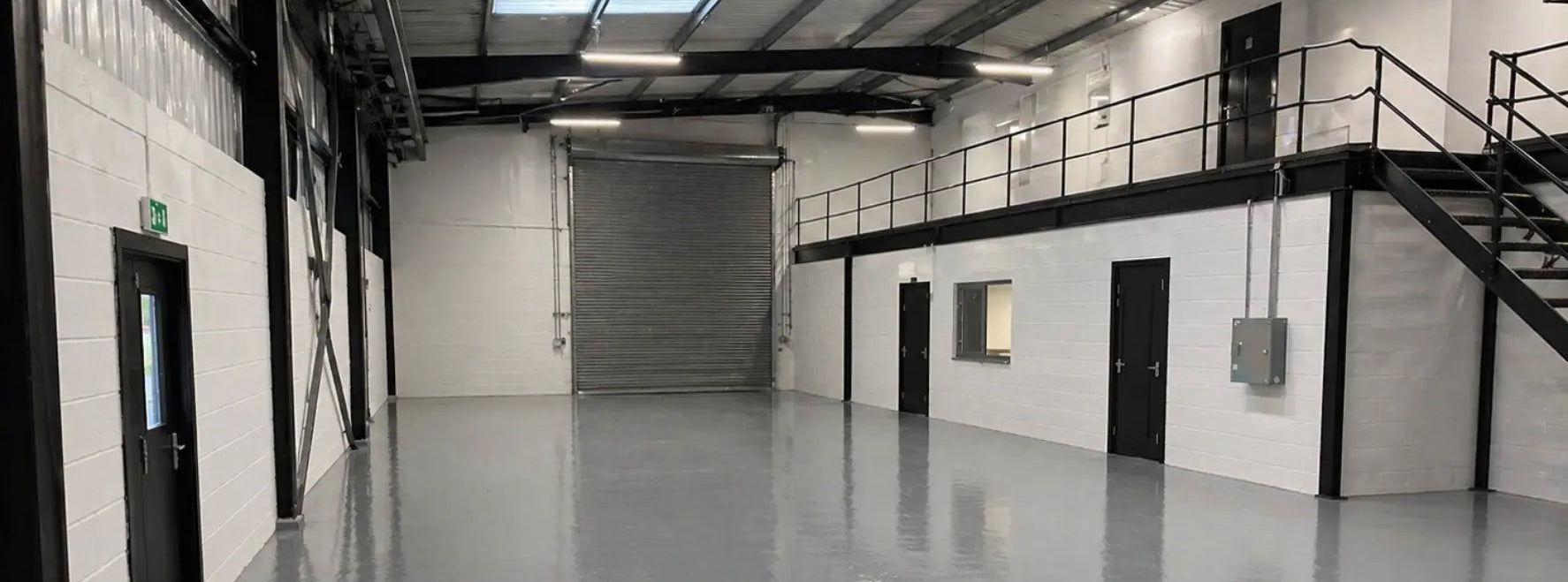 Inside of a painted warehouse showing a grey floor, white walls and black painted steelwork
