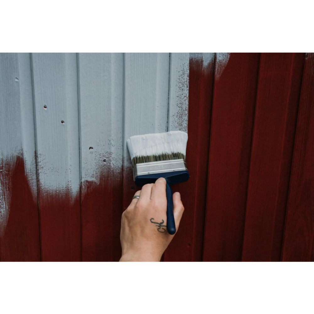 Hand painting a wooden surface with a brush, transitioning from gray to red.