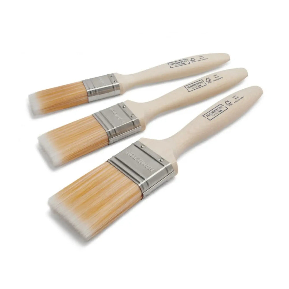 Set of three paint brushes with wooden handles and metal ferrules on a white background