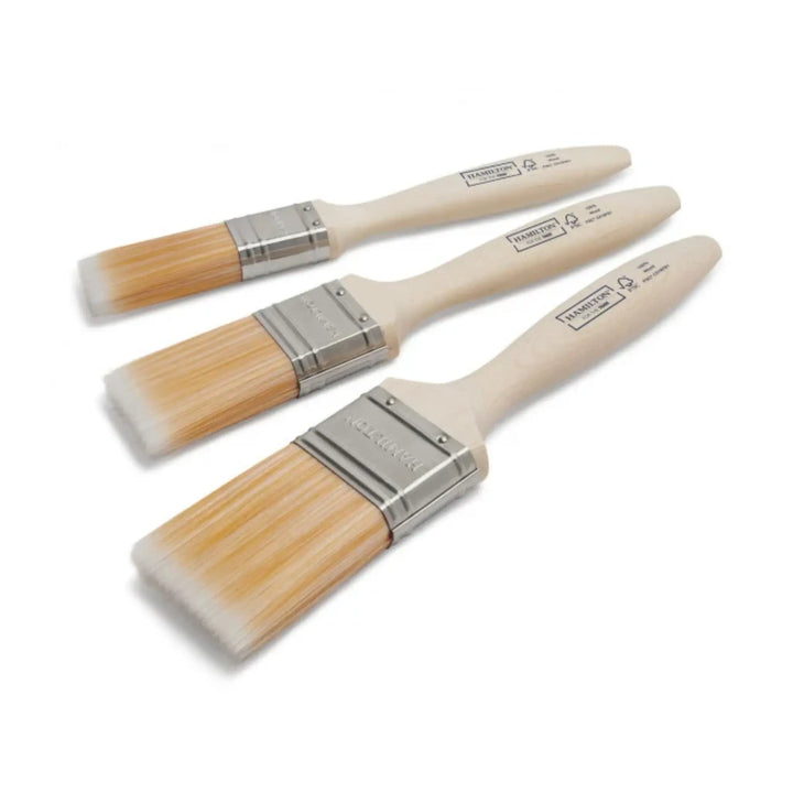 Set of three paint brushes with wooden handles and metal ferrules on a white background