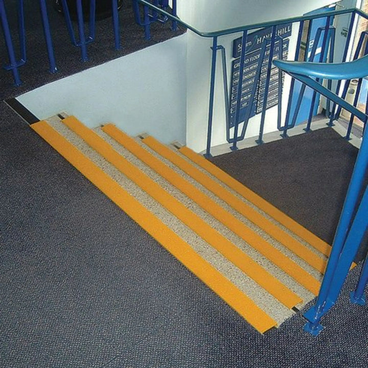 Yellow wheelchair ramp leading up to a set of stairs with blue handrails.