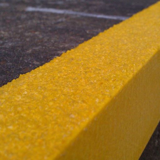 Close-up of a yellow concrete GRP Step Edge on a dark surface