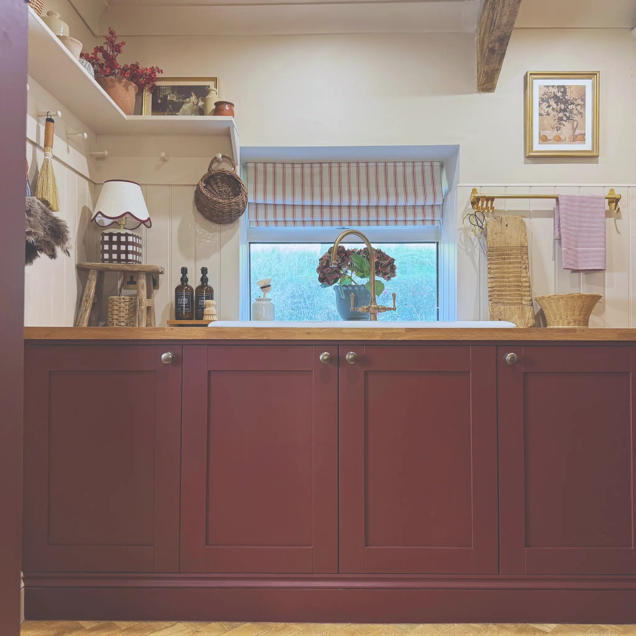 Kitchen with red cabinets, wooden countertop, and window with striped curtain.