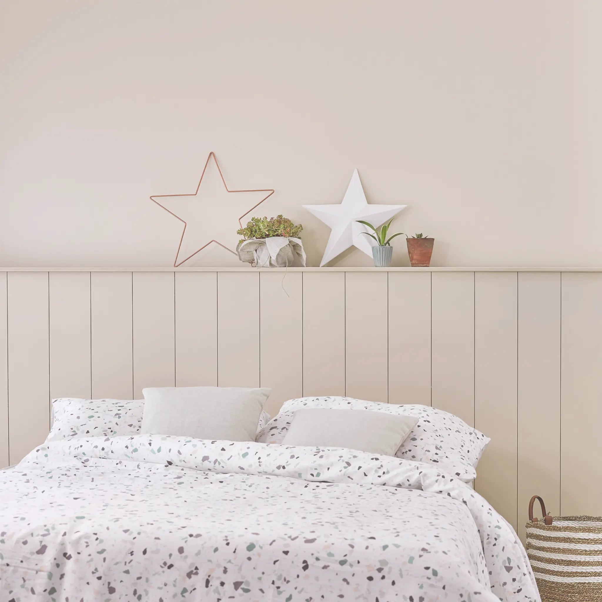 Neatly made bed with white bedding against a wooden headboard with decorative stars.