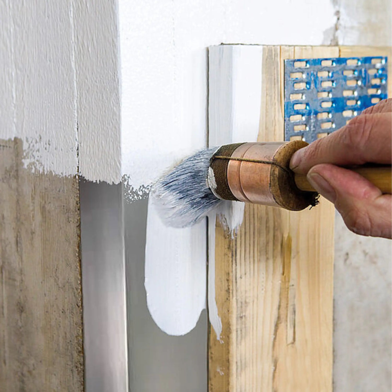 Man painting multiple surfaces with a white paint and paint brush 