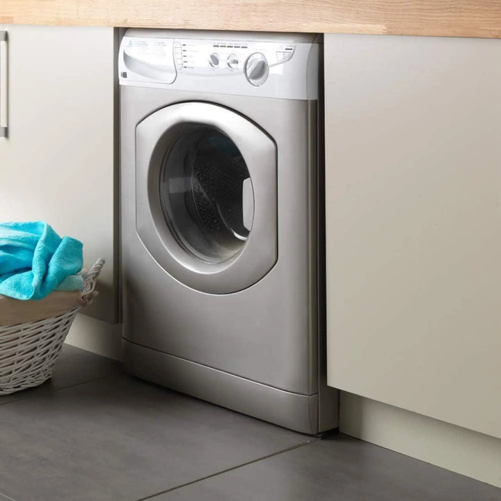 Silver dryer in a laundry room with a basket of clothes nearby.