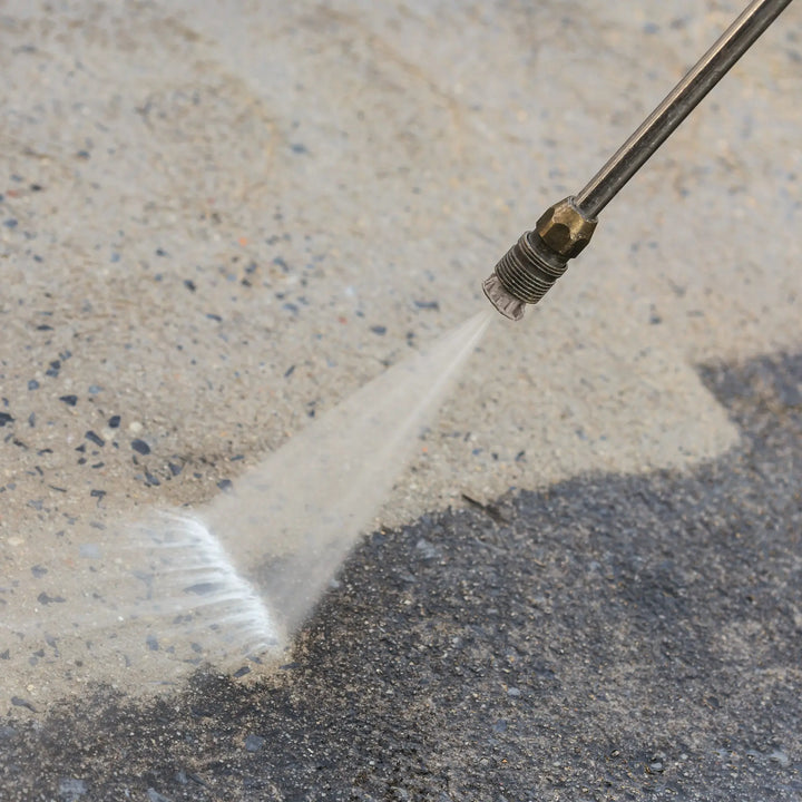 High-pressure water cleaning a concrete surface with a pressure washer nozzle.