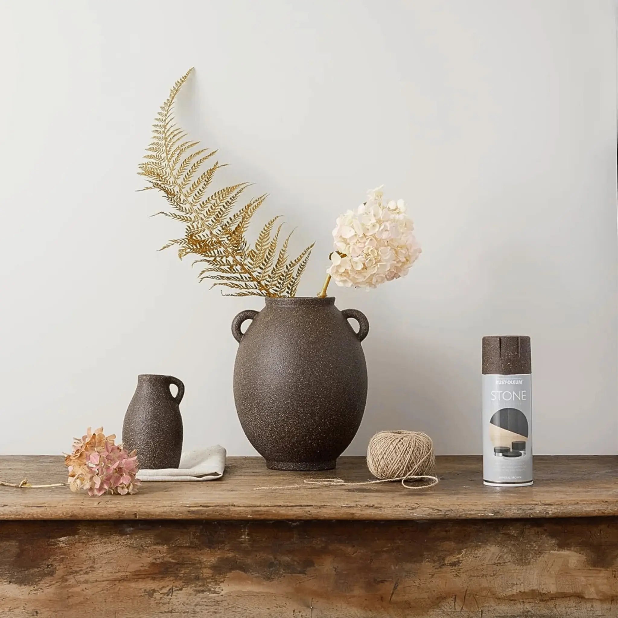 Decorative setting with a large brown vase, smaller vase and Rust-Oleum Textured Stone on a wooden surface.