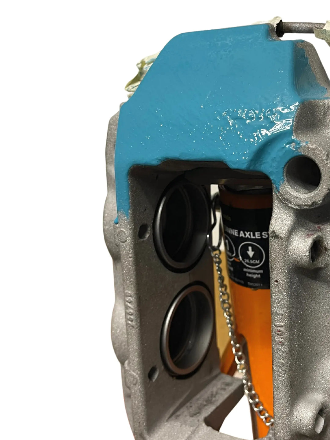 Close-up of a mechanical component with a blue cover and a bottle of lubricant in the background.