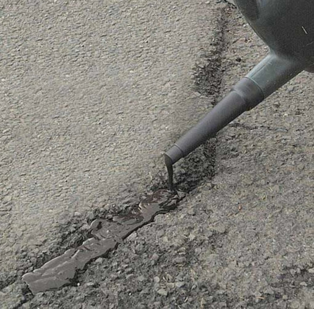 Person using a tool to repair a crack in concrete pavement